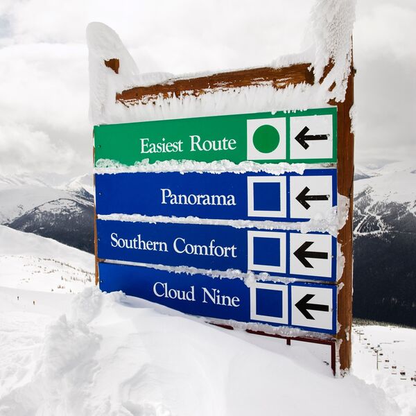 Snow covered sign with arrows to slopes
